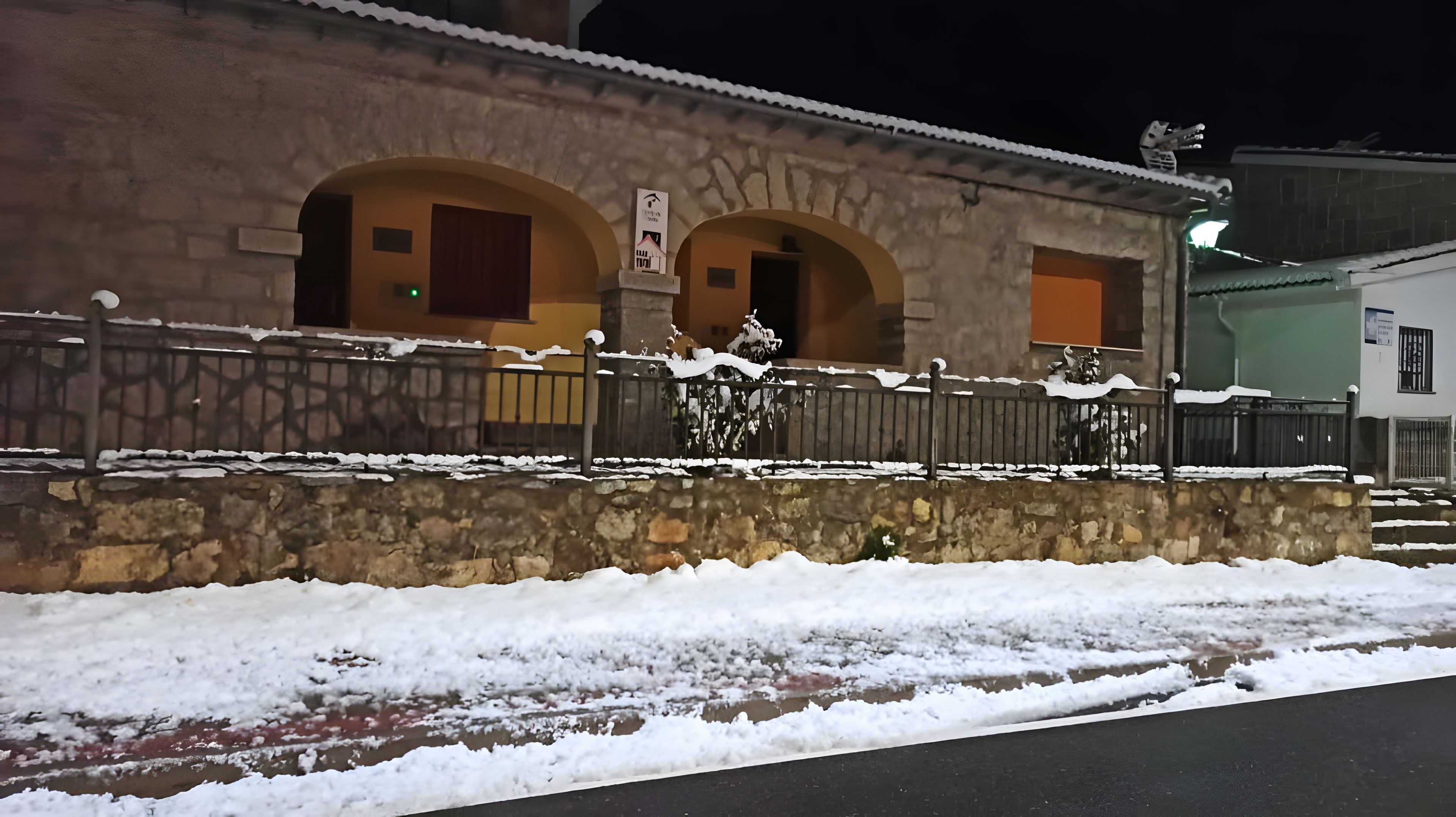 Edificio de piedra con arcos y una valla de metal, rodeado de nieve.