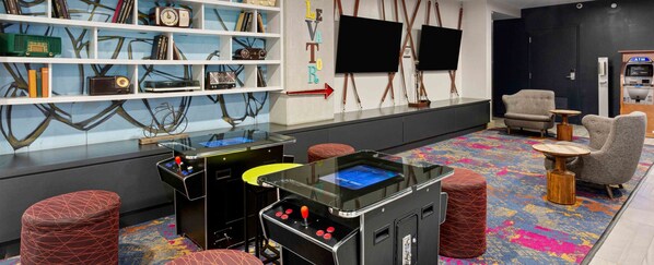 Une salle avec des jeux d’arcade, des coins salon et un mur où sont fixés des téléviseurs.