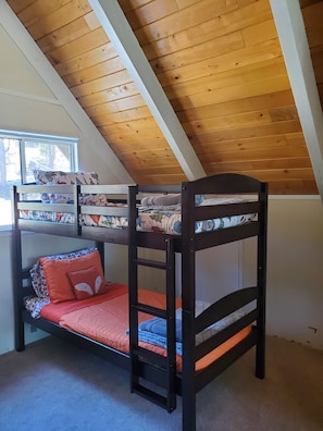 A bunk bed with a lower bunk and a top bunk, both with patterned bedding. - Tranquil 3-bedroom cabin with AC in charming Groveland (Groveland)