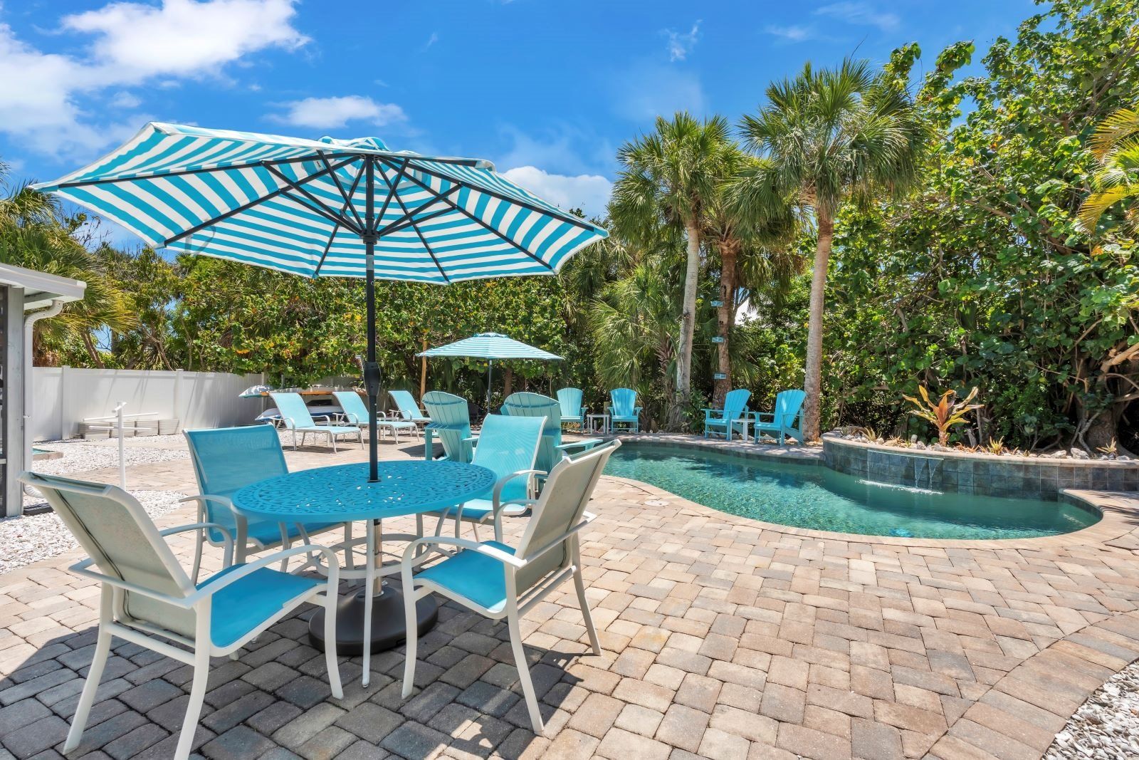 A poolside area with lounge chairs, a table, and a large umbrella.