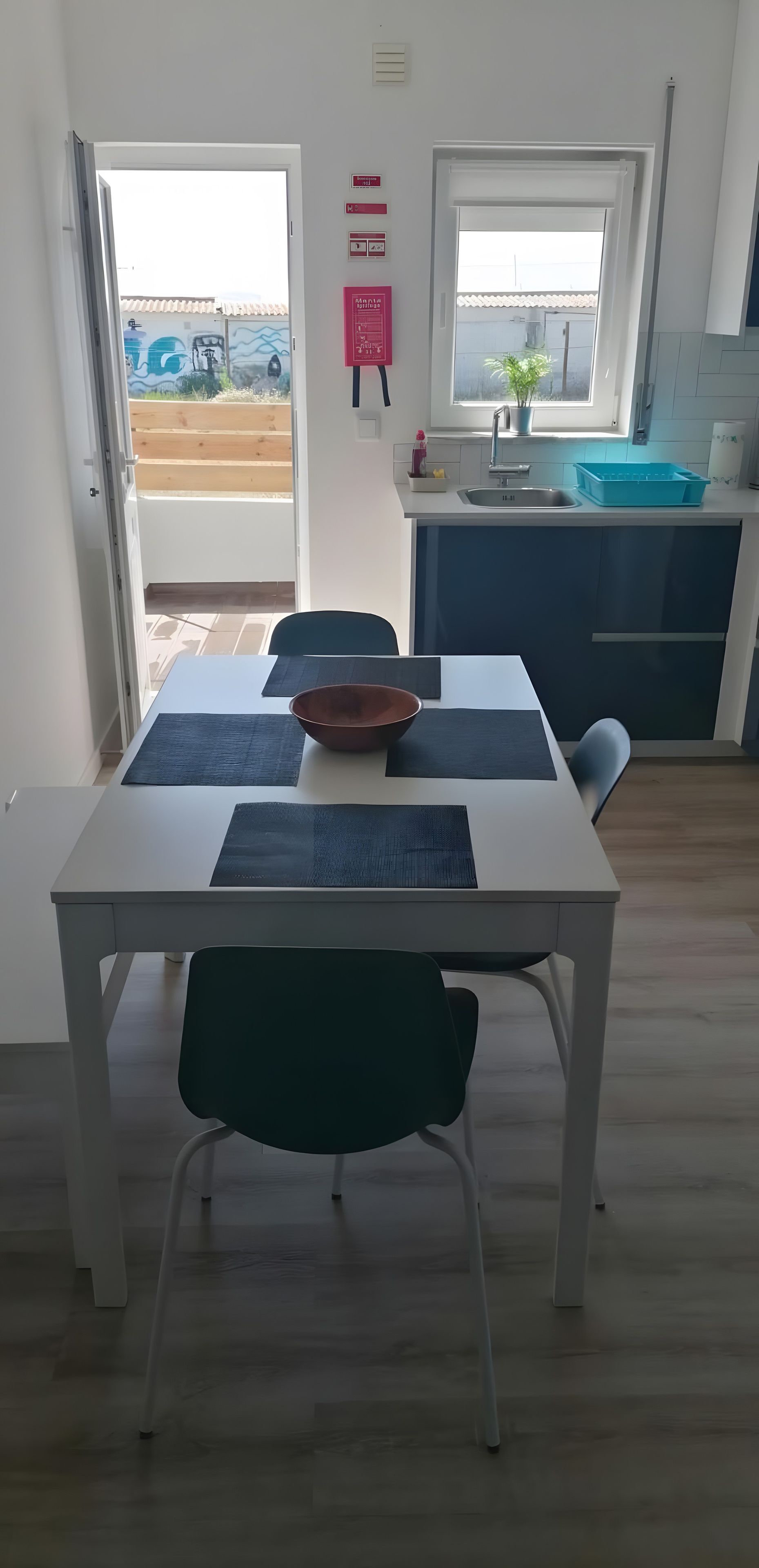 Moderni keittiö, jossa on pesuallas, työtaso ja ikkuna. Keittiössä on myös ruokailutila, jossa on pöytä ja tuolit.