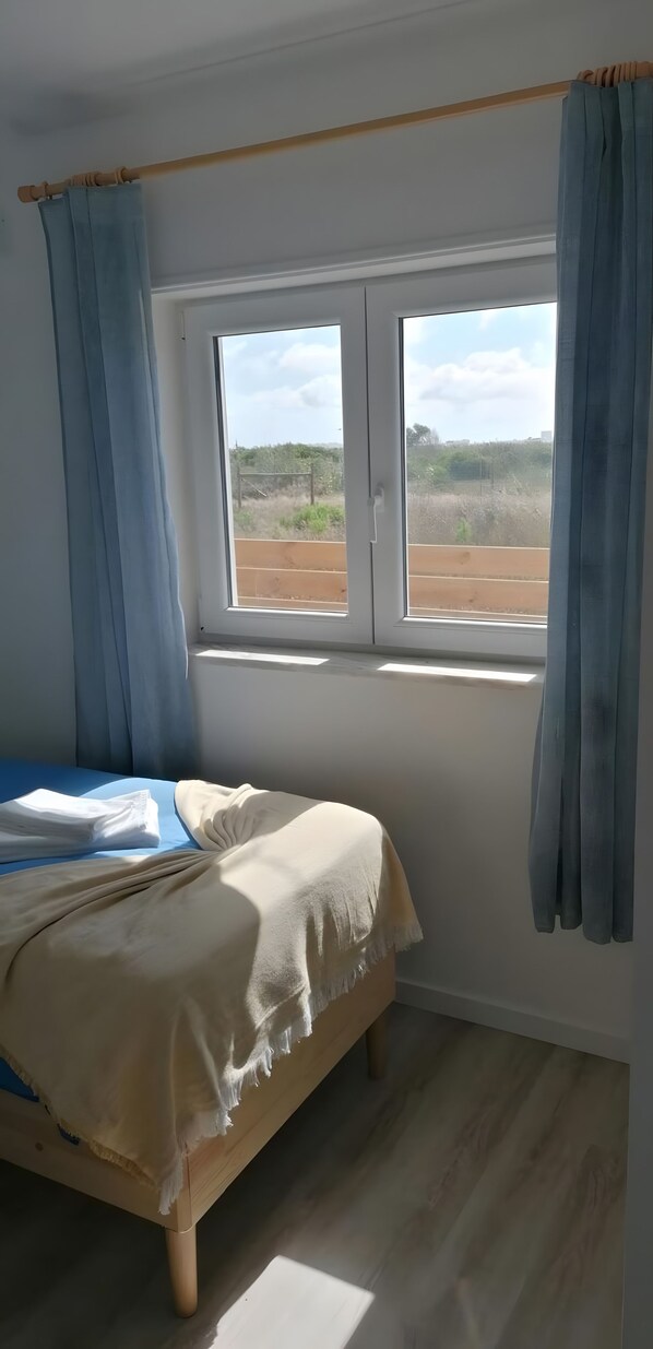 Een kamer met een bed, een raam en gordijnen.