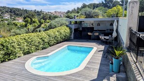 A swimming pool with a wooden deck, surrounded by greenery, and a seating area with outdoor furniture. - New Listing (Les Pennes-Mirabeau)