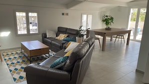 A living room with a sofa, coffee table, and a dining table with chairs. There is a potted plant on the dining table. - New Listing (Les Pennes-Mirabeau)