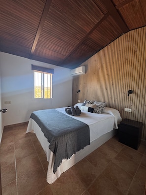 A bedroom with a bed, a window, an air conditioning unit, and a nightstand. - Country House 'Villa Fernandez' with Mountain Views, Wi-Fi and Air Conditioning (Ojén)