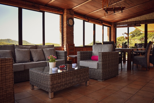 Un grand espace extérieur aménagé avec des meubles en osier, une table et une vue sur les collines.