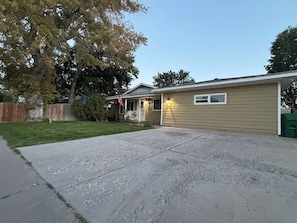 A residential house with a front yard, a driveway, and a wooden fence. - Capitol Outpost Hot Tub Pet friendly fenced Yard fire pit (Carson City)
