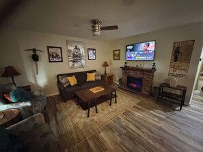 A living room with a fireplace, a television, and a sofa. - Capitol Outpost Hot Tub Pet friendly fenced Yard fire pit (Carson City)