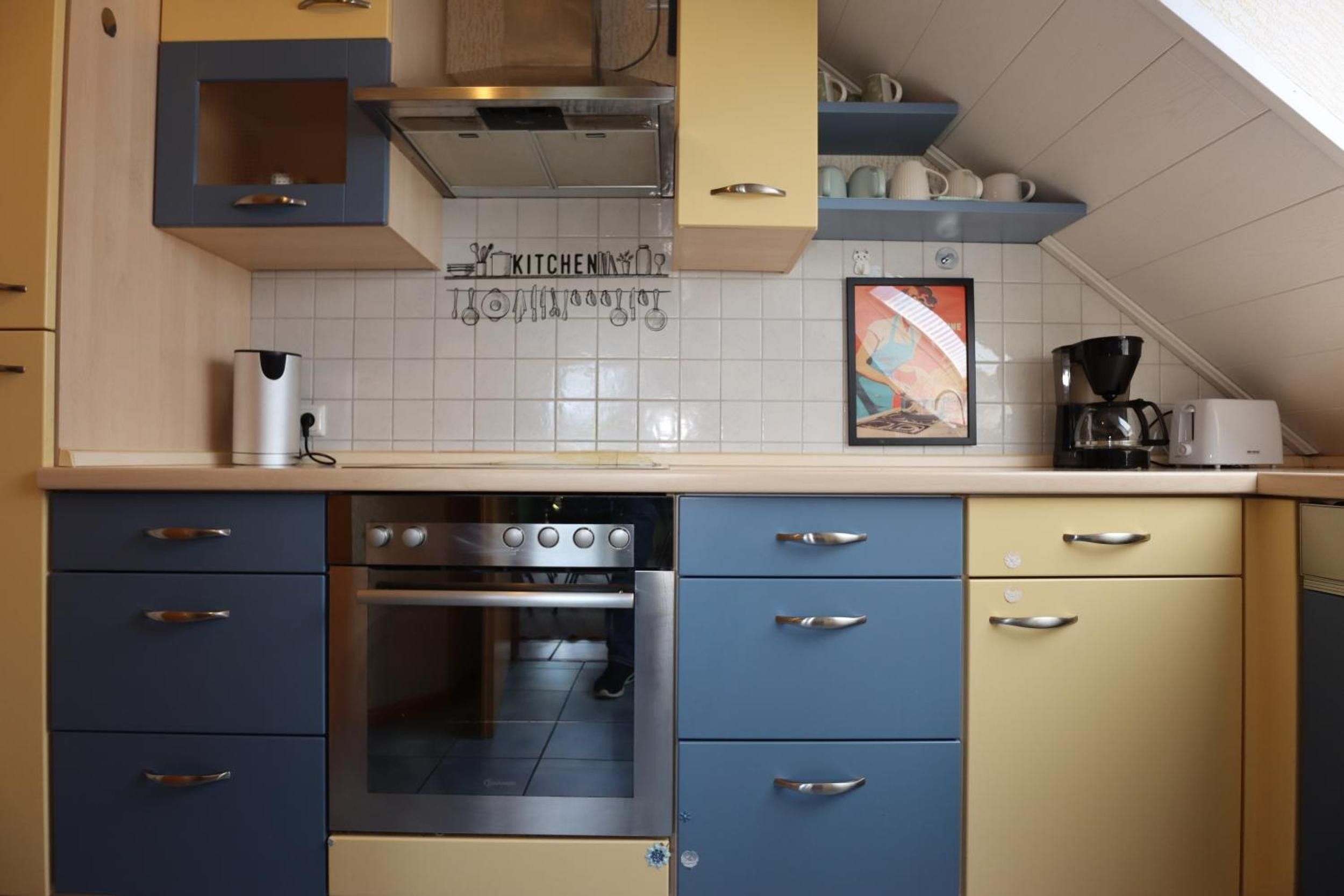 A kitchen with a built-in oven, a coffee maker, and a tiled backsplash.