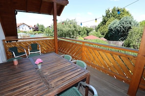 En träaltan med ett bord och stolar, med utsikt över ett bostadsområde med träd och hus.