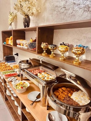 A buffet setup with various food items and serving dishes. - The Moonya Hotel (Samarqand)