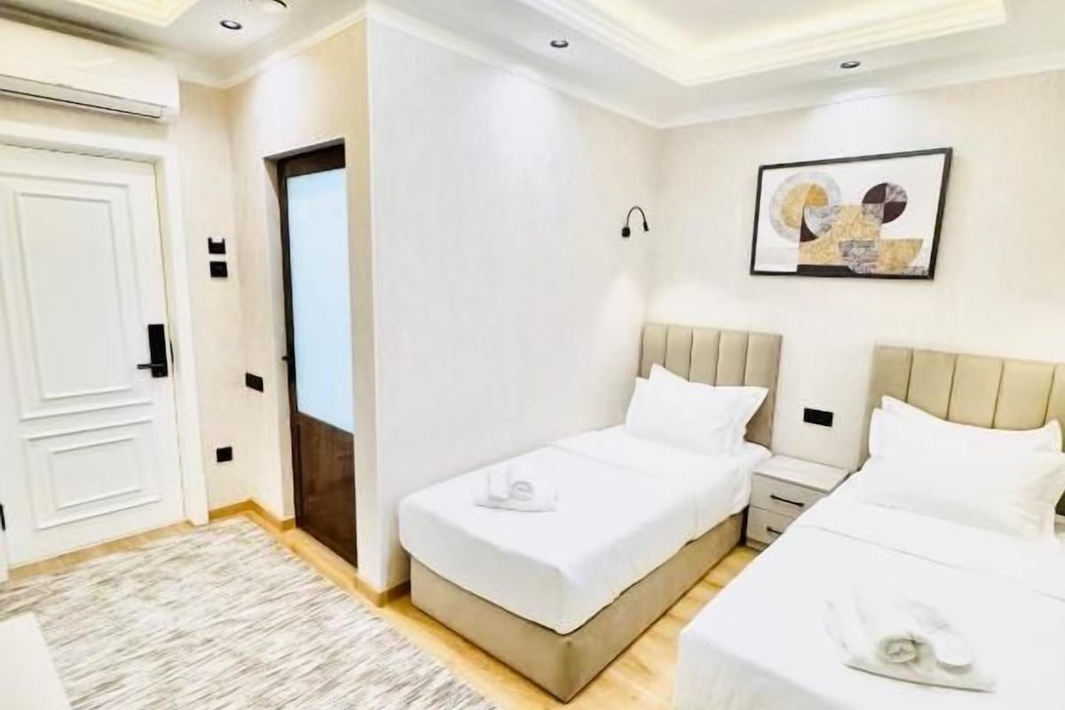 A hotel room with two beds, a desk, and a chair.