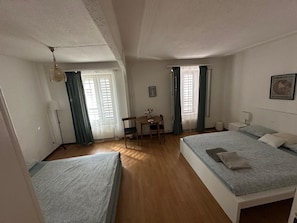 Habitació d'hotel amb dos llits, una taula petita amb cadires i una finestra amb cortines.