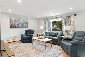 A modern living room with a sofa, two armchairs, a coffee table, and a painting on the wall.
