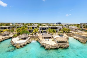 Et resort med overvandsbungalows, krystalklart turkis vand og palmer.