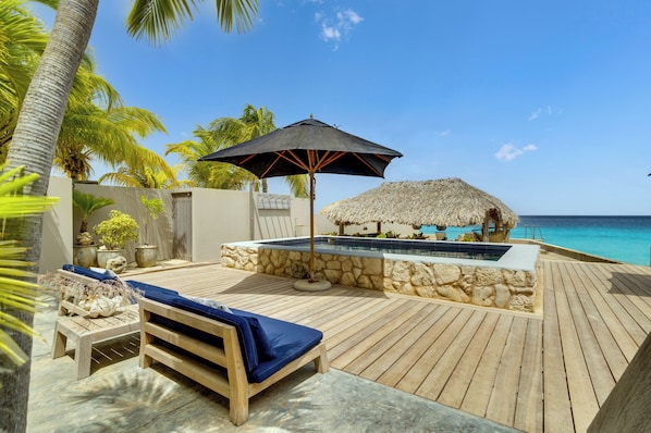 A wooden deck with a pool, lounge chairs, and a thatched-roof structure. - New Listing (Kralendijk)