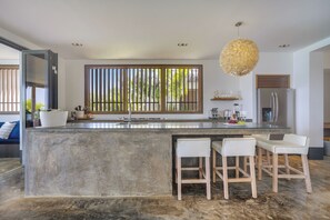 A modern kitchen with a large island, bar stools, a refrigerator, and a hanging light fixture. - New Listing (Kralendijk)