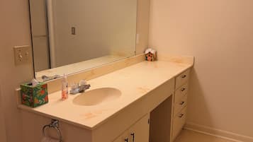 A bathroom with a large mirror, a sink, and a vanity with drawers.