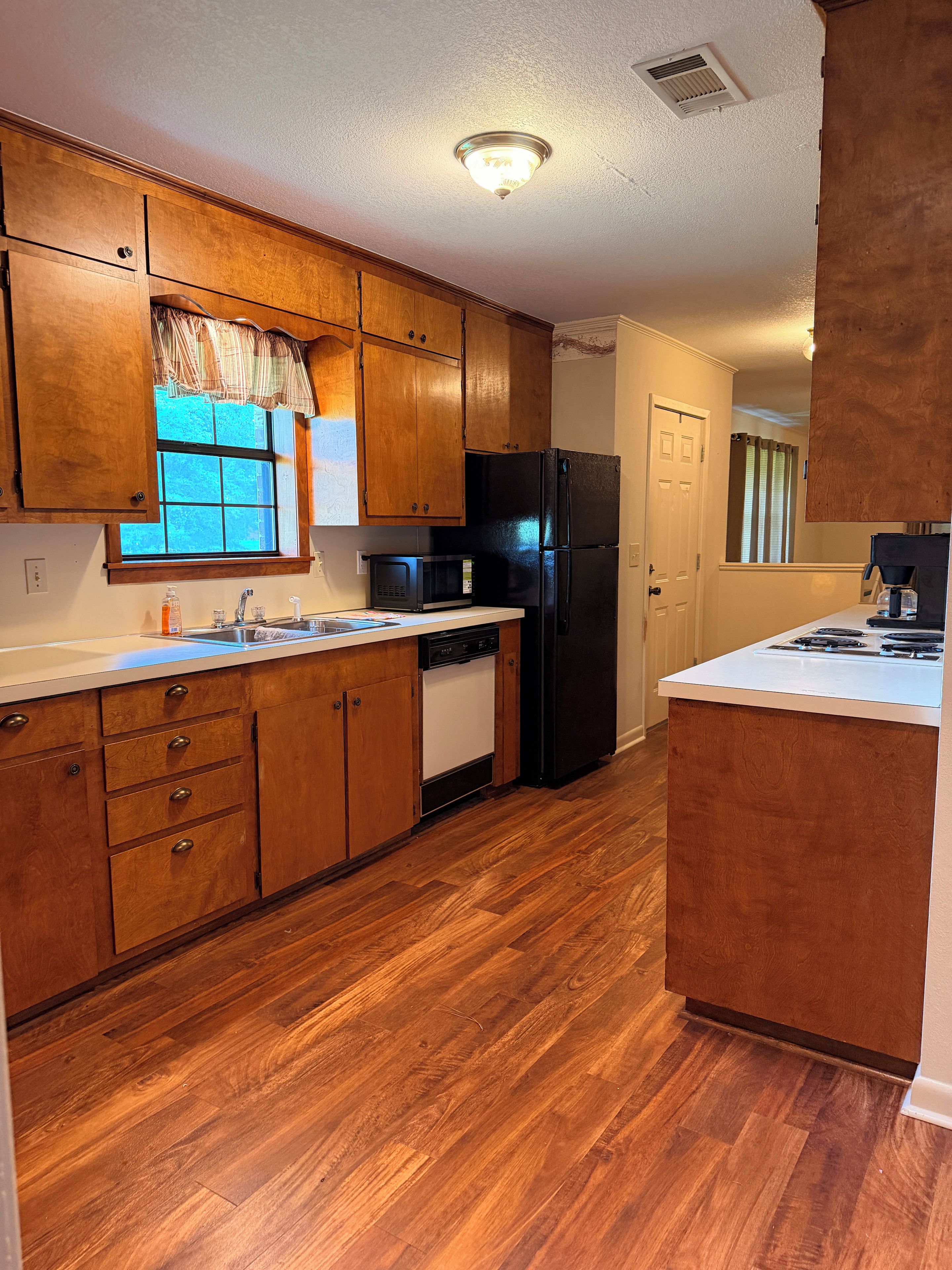 A kitchen with wooden cabinets, a black refrigerator, a microwave, and a dishwasher.