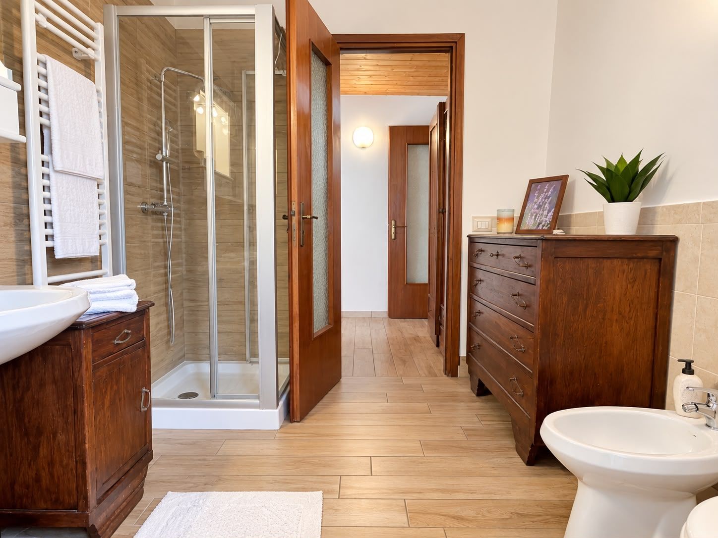 Un bagno moderno con doccia vetrata, mobili in legno e lavabo bianco.
