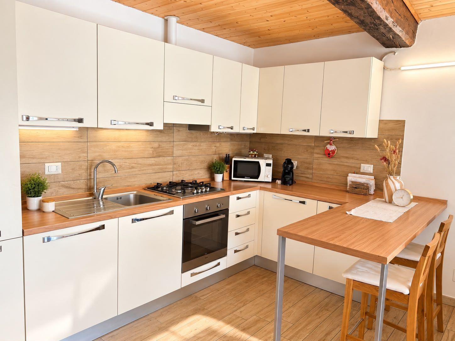 A modern kitchen with white cabinets, stainless steel appliances, and a wooden dining table.