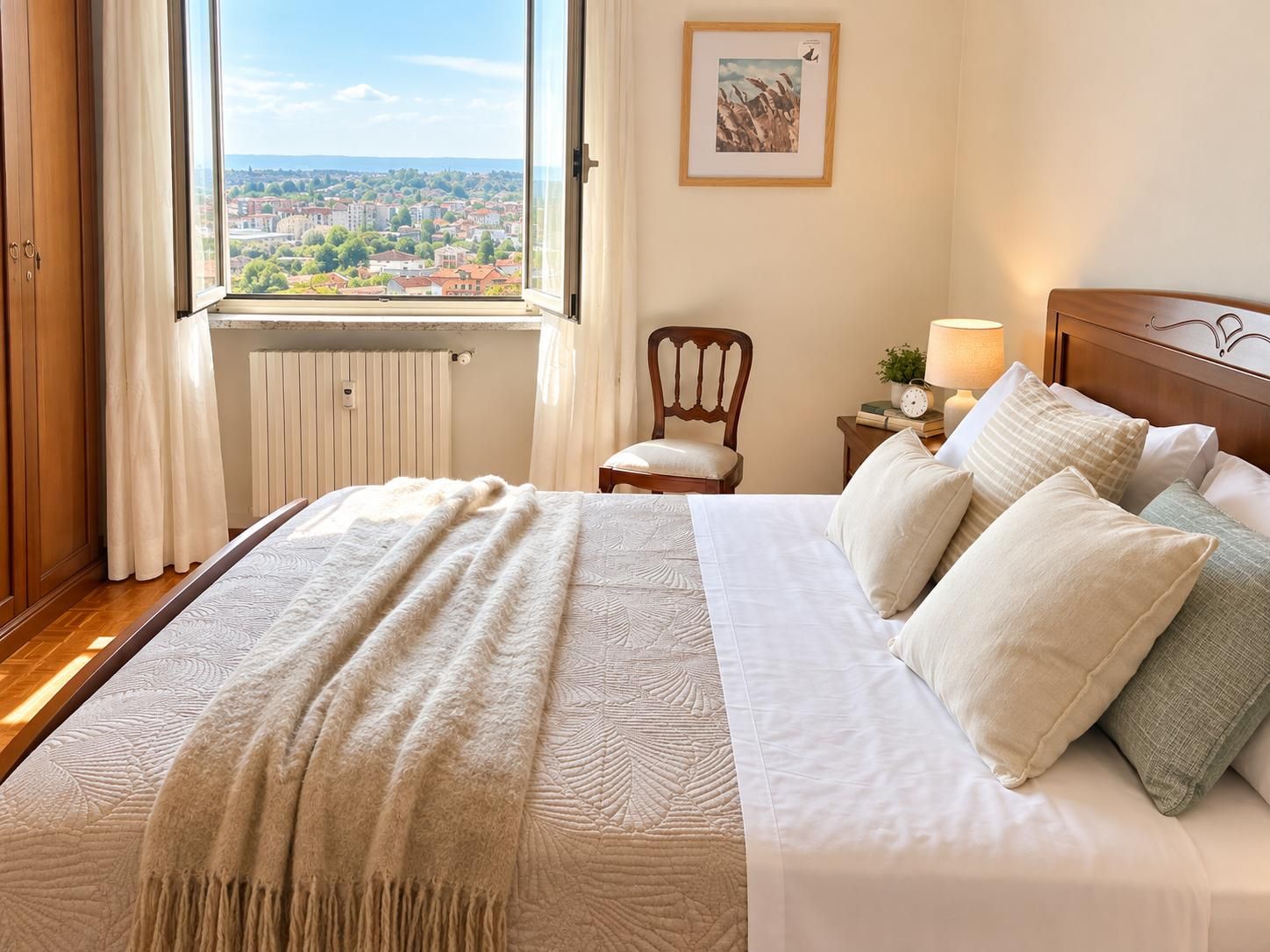 Une chambre d’hôtel avec un grand lit, une vue sur la ville, une tête de lit en bois et une table de chevet avec une lampe.