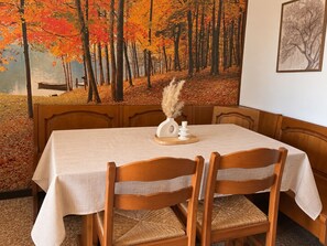 A dining area with a table set for four, wooden chairs, and a wall mural of a forest scene. - QuickHome Panorama - Two Bedroom Apartment, Sleeps 4 (Cossato)