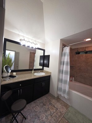 Une salle de bain dotée d’un grand miroir, d’un meuble-lavabo, d’un évier et d’un espace douche.