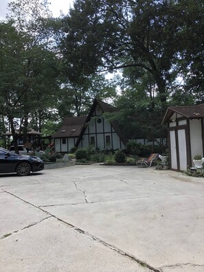 A residential property with a driveway, a house with a gabled roof, and a fenced garden area. - Chestnut Cottage at Saluda River Farms (Greenville)