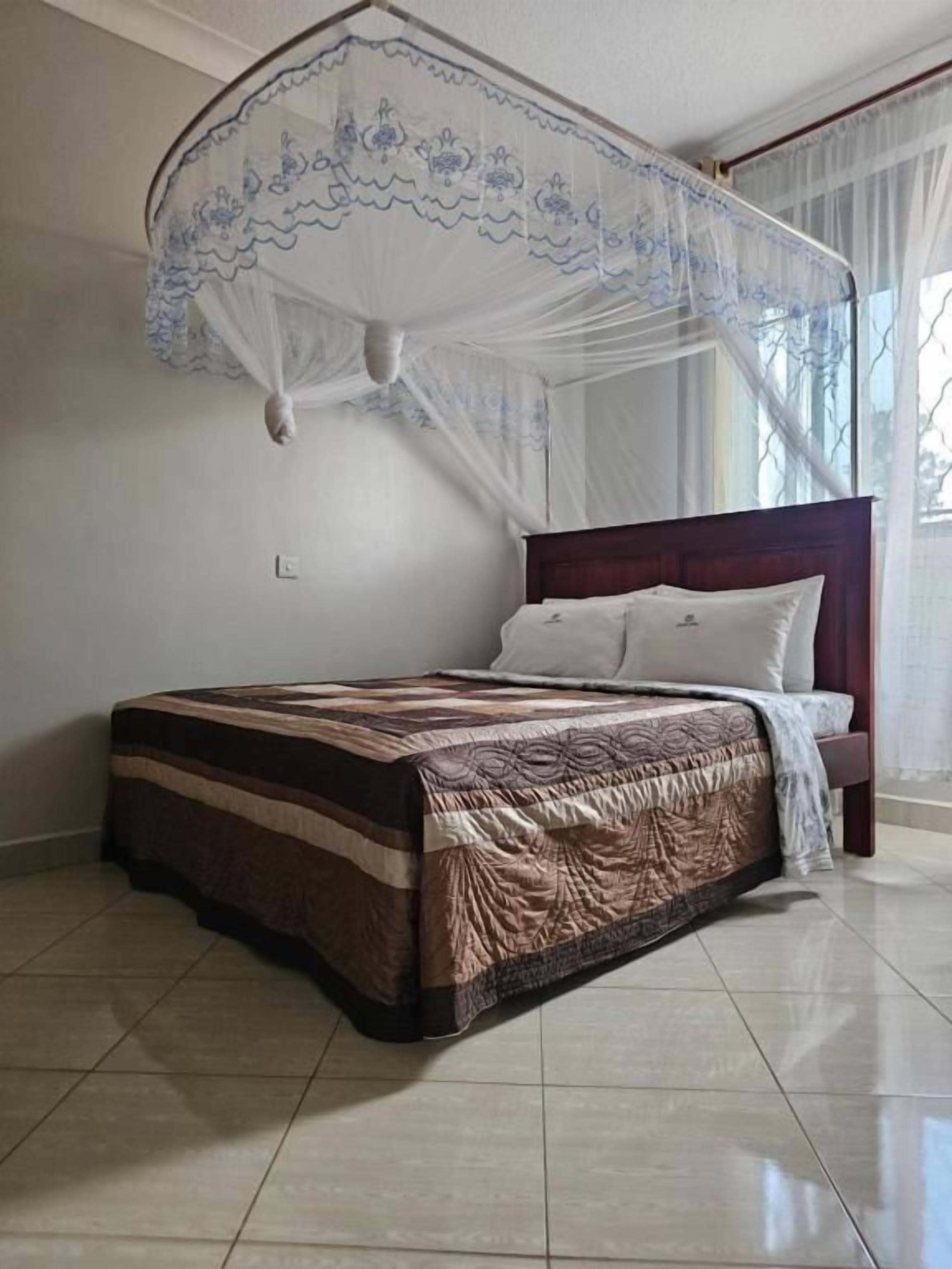 A bedroom with a bed, a canopy, and a window with curtains.