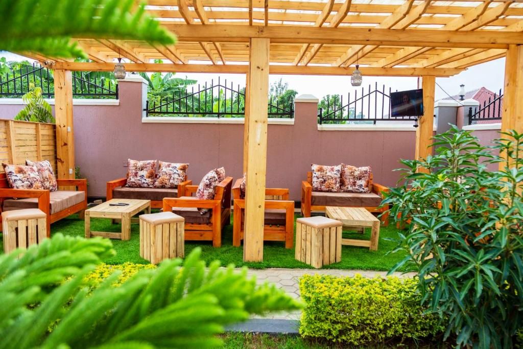 A wooden outdoor seating area with tables and chairs, surrounded by greenery and a pergola structure.
