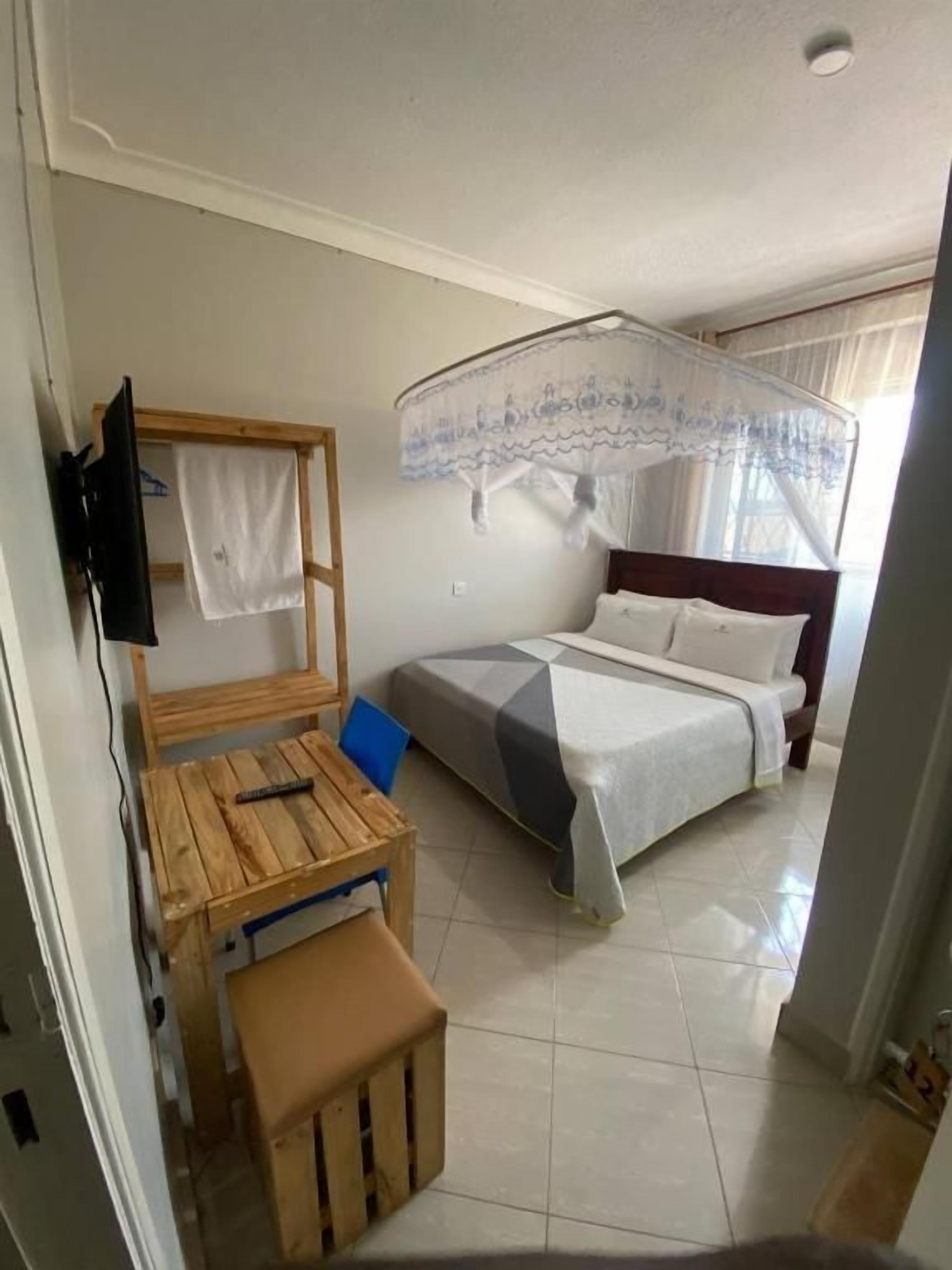 A bedroom with a bed, a bedside table, a chair, and a wooden bench.