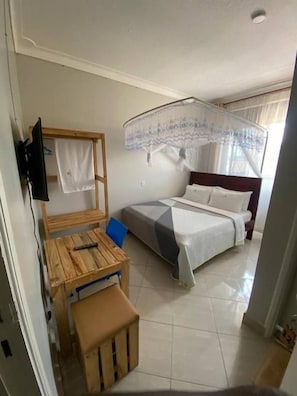 Ein Schlafzimmer mit einem Bett, einem Nachttisch, einem Sessel und einer Holzbank.