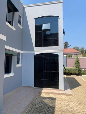 Un edificio de dos pisos con ventanas amplias y un patio empedrado.
