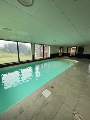 Ein Hallenbad mit Blick auf eine bewaldete Landschaft durch große Fenster.