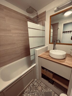 Ein Badezimmer mit einer Badewanne, einem Waschbecken und einem Spiegel.