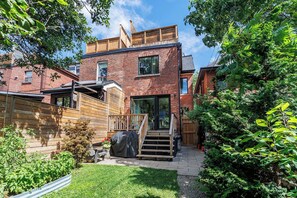 A two-story brick house with a wooden deck, a covered outdoor seating area, and a small garden. - 3 bed · 2 bath · Sauna · Garden · 2 Car Parking Pad (Toronto)