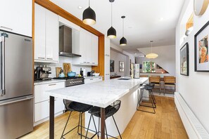 A modern kitchen with a central island, pendant lighting, and a dining area with a view. - 3 bed · 2 bath · Sauna · Garden · 2 Car Parking Pad (Toronto)