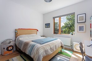 A bedroom with a bed, a radiator, a window with a view, and a desk with a chair. - 3 bed · 2 bath · Sauna · Garden · 2 Car Parking Pad (Toronto)
