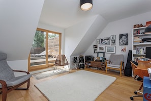 A loft-style room with a sloped ceiling, a large window, and a collection of framed photographs on the wall. - 3 bed · 2 bath · Sauna · Garden · 2 Car Parking Pad (Toronto)