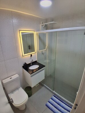 Une salle de bain équipée de toilettes, d’un lavabo et d’une douche à parois de verre.