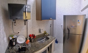 Une cuisine équipée d’un four à micro-ondes, d’un évier et d’un réfrigérateur en acier inoxydable.
