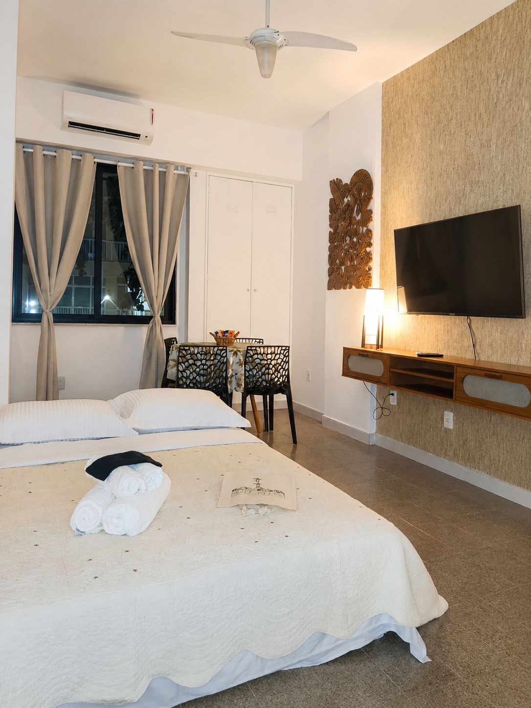 A hotel room with two beds, a TV, a desk with a chair, and a decorative wall piece.
