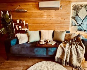 A cozy living room with a blue sofa, a wooden wall, a bookshelf, and a decorative stone wall. - AYDER Diamond River (Camlihemsin)