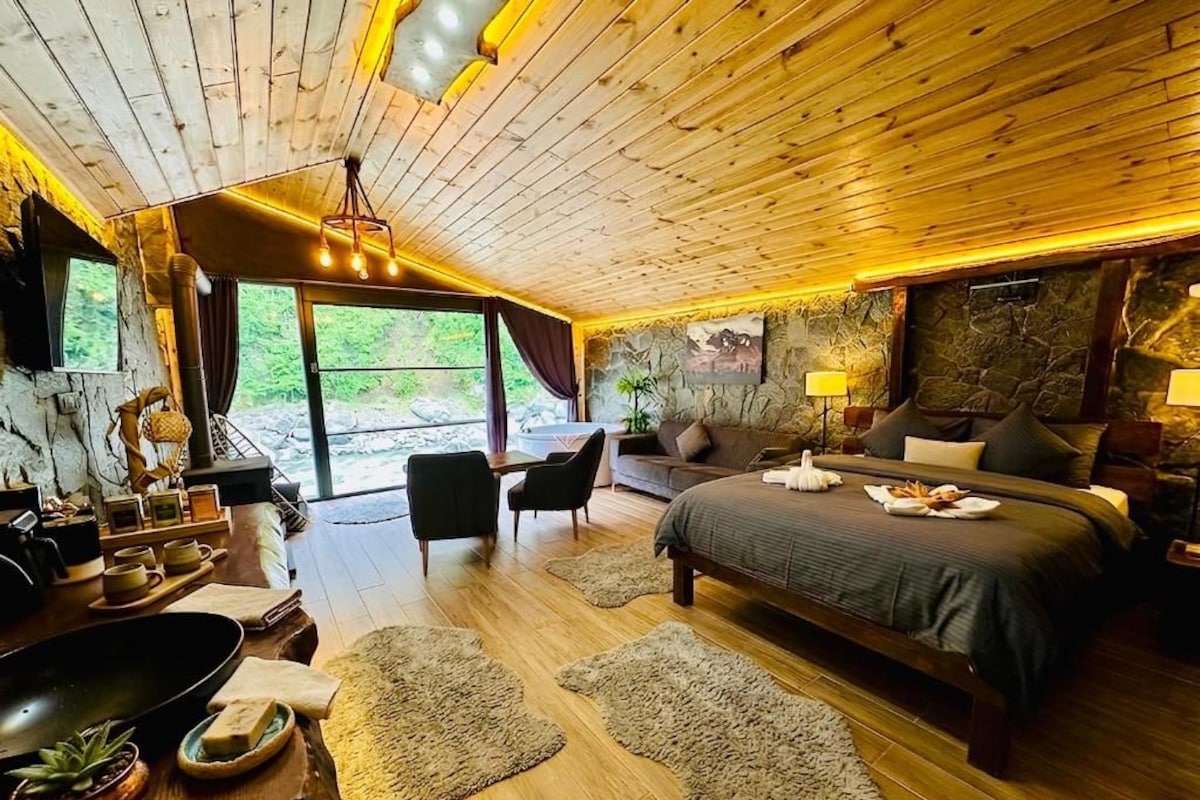 A wooden-paneled room with a bed, a dining table, and a view of the outdoors.