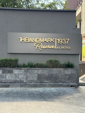 A sign for 'THELANDMARK 1937 Reserve AV. PATRIA' with a stone wall and plants in front. - New Listing (Zapopan)