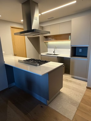 A modern kitchen with a central island, built-in oven, and stainless steel range hood. - New Listing (Zapopan)