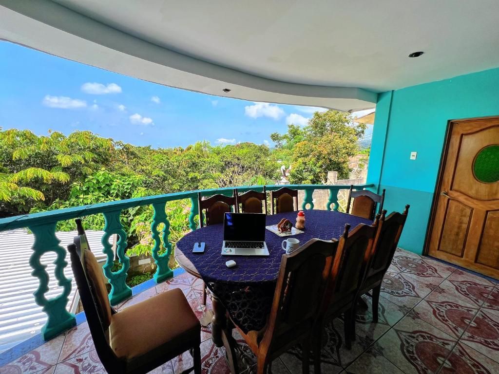 Een balkon met een tafel, stoelen en een laptop.