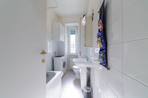 Un baño con bañera, inodoro y lavadora.