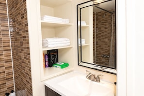 A bathroom with a white sink, a mirror, and shelves with folded towels and a hair dryer. - Modern DC Basement WiFi - Free Parking (Washington)